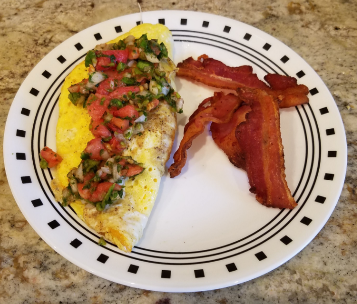 eggs with pico de gallo on a white plate with bacon