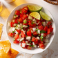 pico de gallo in a white bowl with lime wedge garnish next to chips